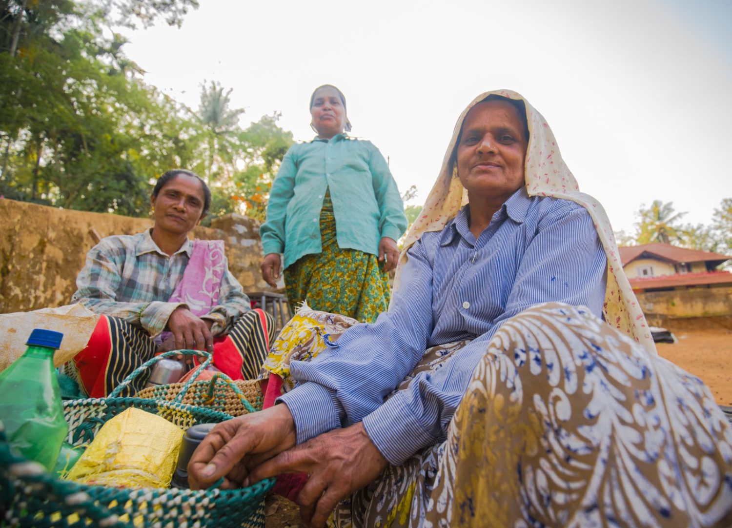 A group from the Coorg estate sitting together outside at the end of a working day